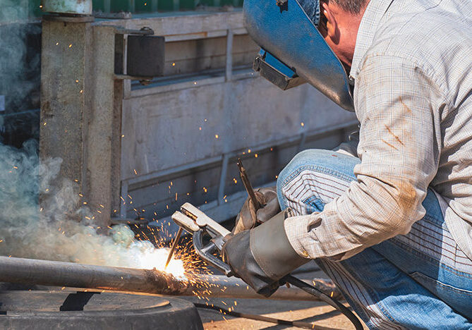 AdobeStock_938249460 Welder is welding galvanized steel pipe for improvement building structure at outdoor workshop in construction site area